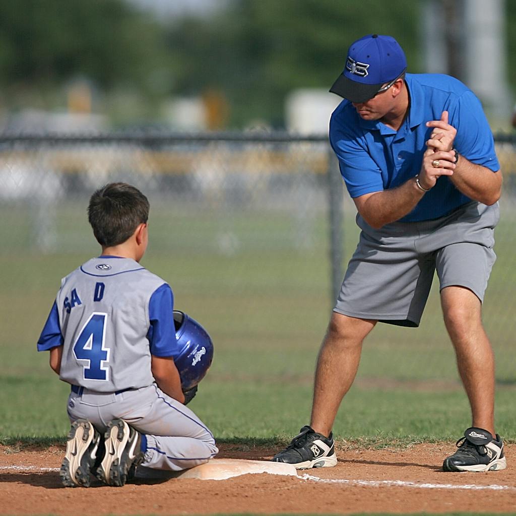 Man Kneeling on Baseball Field Beside Man